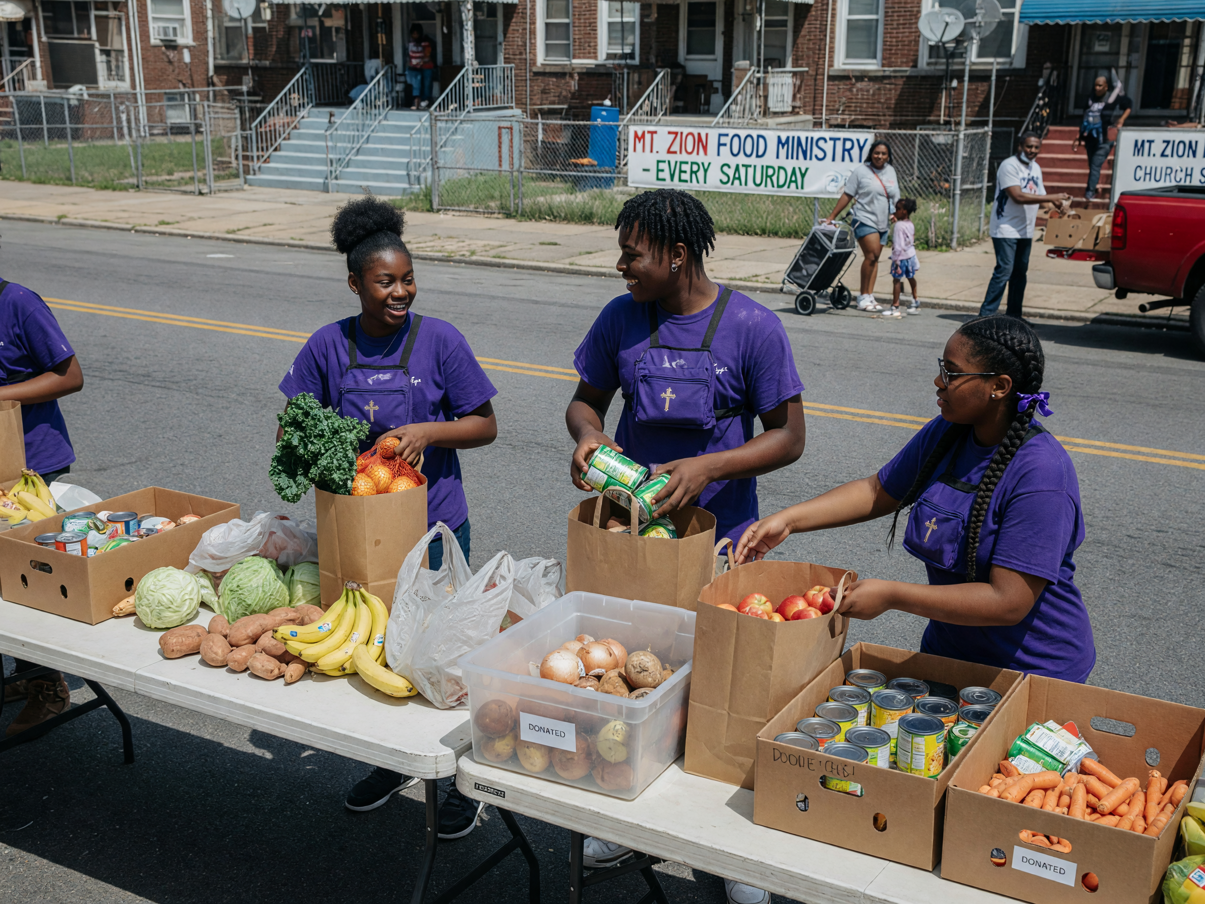 Young people packing food bags at an outdoor distribution